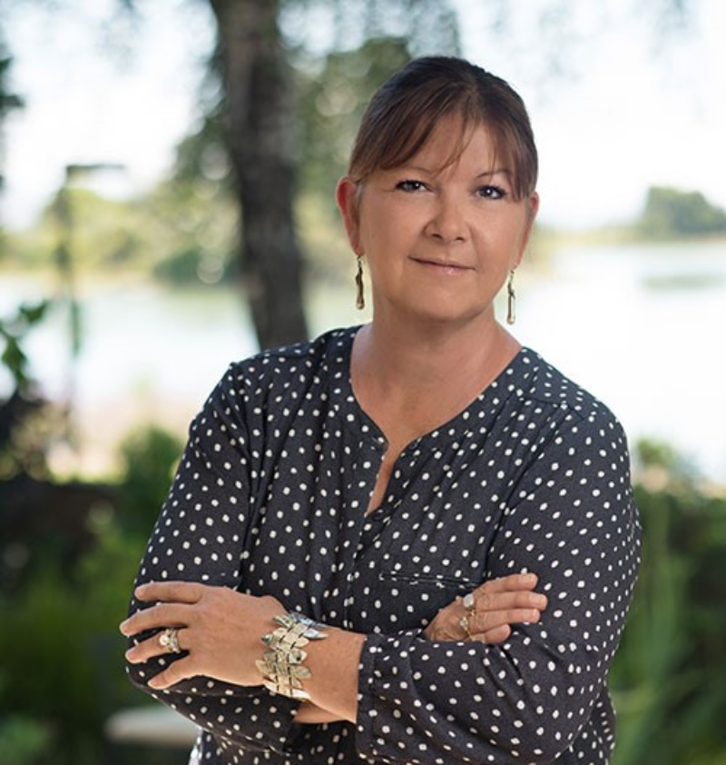 Woman standing outdoors with arms crossed.