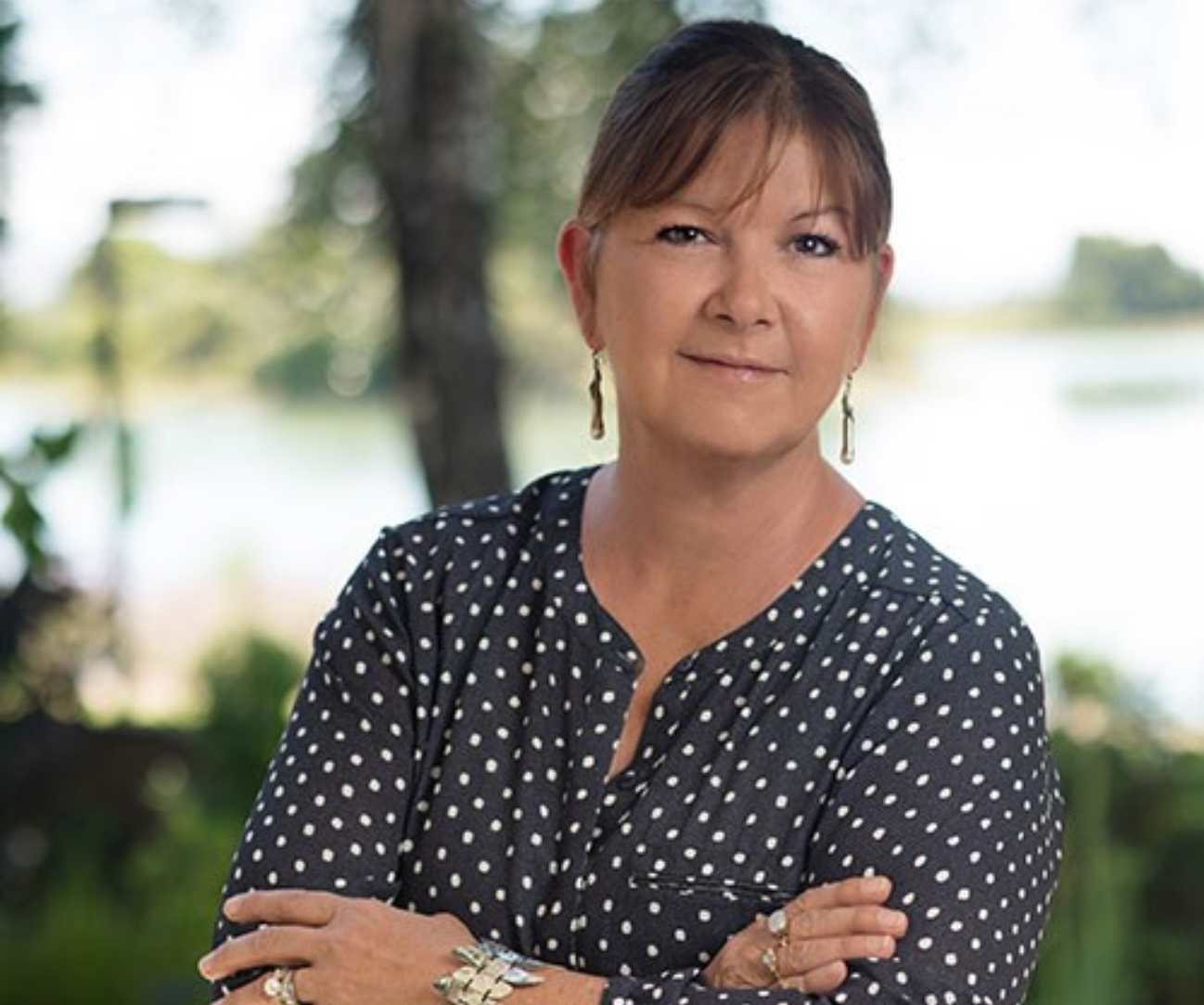 Woman in polka dot blouse outdoors.