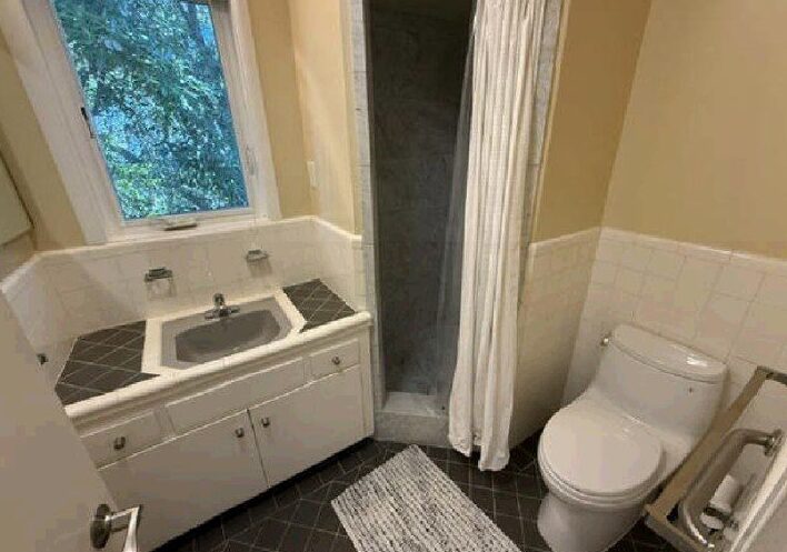 Small beige bathroom with shower, sink, toilet