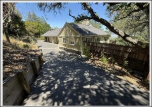 Yellow cottage on oak-shaded driveway