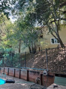 Backyard pool with hillside house and fence