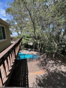 Wooden backyard deck overlooking swimming pool and trees