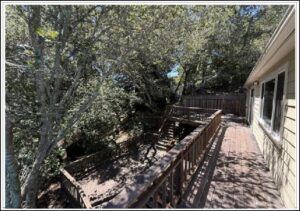 Sunlit multi-level wooden deck beside house