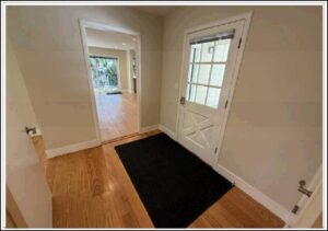 Entryway with white door and black rug