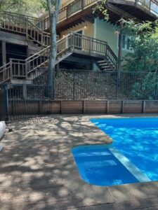 Blue backyard pool with wooden deck and stairs