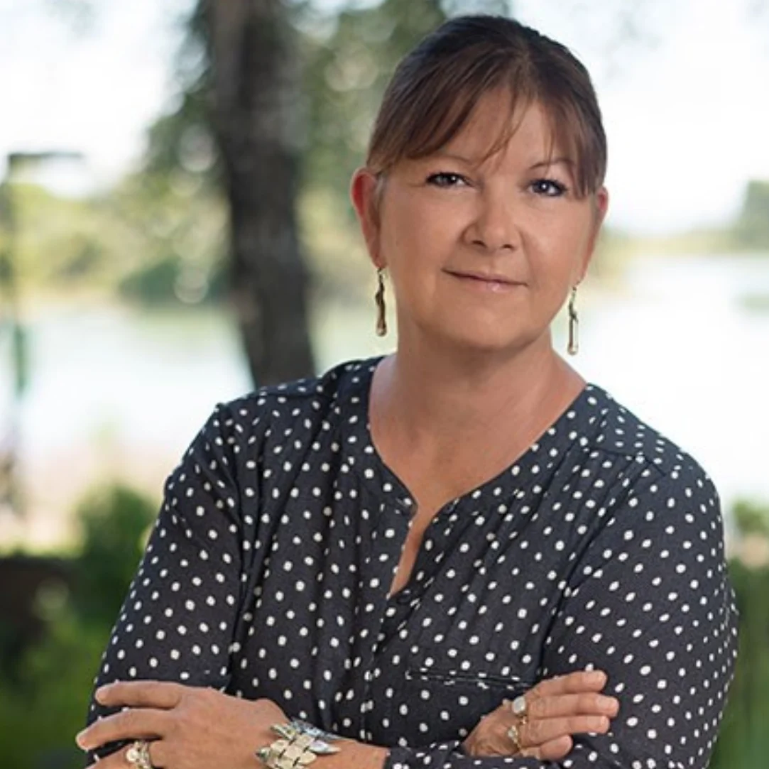 Woman in polka dot blouse outdoors.